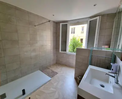 a bathroom with a tub and a sink and a window at Bel appartement 2 chambres climatisé centre ville in Nice