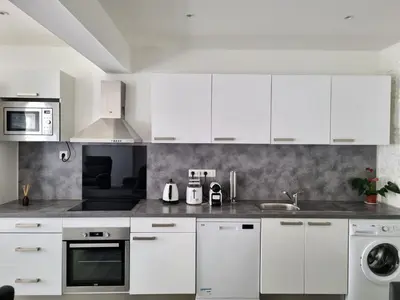 a white kitchen with white cabinets and a sink at Bel appartement 2 chambres climatisé centre ville in Nice