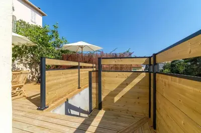 a wooden deck with a fence and an umbrella at Magnifique pavillon indépendant T2 Nice in Nice
