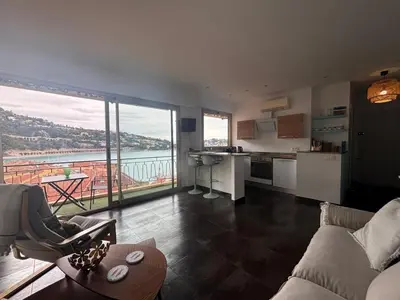 a living room with a couch and a kitchen with a view at Excellent location - Sea Views in Villefranche-sur-Mer
