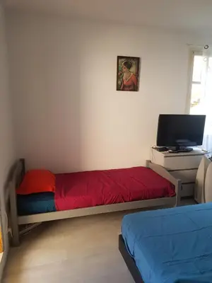 a bedroom with a bed and a desk with a television at studio pour 3 personnes au calme dans villa in Nice