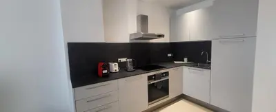a kitchen with white cabinets and a black counter top at cagnes promenade in Cagnes-sur-Mer