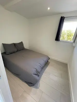 a bed in a room with a window at appartement bas de villa avec piscine privée partagée proche bord de mer in Cagnes-sur-Mer