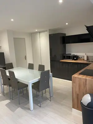 a dining room with a table and chairs in a kitchen at appartement bas de villa avec piscine privée partagée proche bord de mer in Cagnes-sur-Mer