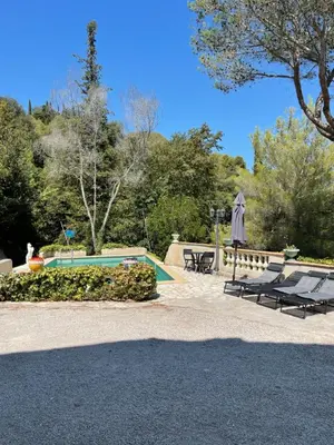 a swimming pool with two lounge chairs and an umbrella at appartement bas de villa avec piscine privée partagée proche bord de mer in Cagnes-sur-Mer