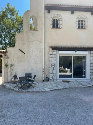 two chairs and a table in front of a building at appartement bas de villa avec piscine privée partagée proche bord de mer in Cagnes-sur-Mer