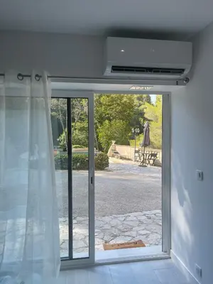 a sliding glass door with a view of a yard at appartement bas de villa avec piscine privée partagée proche bord de mer in Cagnes-sur-Mer