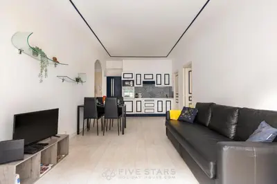 a living room with a black couch and a television at Suite Reine Marie FSHH in Nice