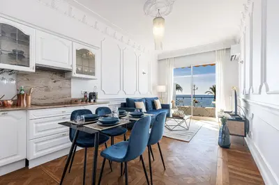 a kitchen with a table and blue chairs in a room at PROMENADE SEA VIEW - Terrasse vue mer in Nice