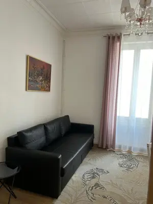 a living room with a black leather couch and a window at Villa Niçoise.3P. 5 min de la plage in Nice