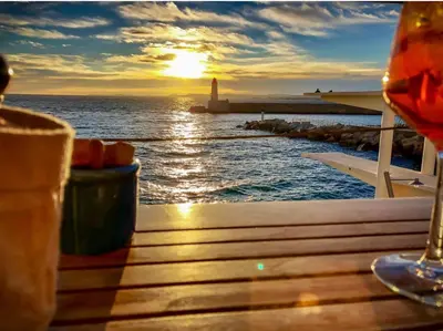 a table with a glass of wine and a lighthouse at Nice Vieille Ville Appartement neuf et cosy, deux chambres, 6 couchages in Nice