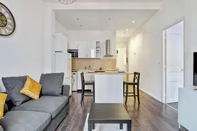 a living room with a couch and a kitchen at Appartement Oscarmony - Welkeys in Nice