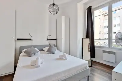 a white bedroom with a large bed and a window at Appartement Oscarmony - Welkeys in Nice
