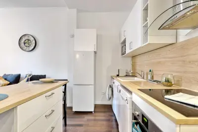 a kitchen with white cabinets and a sink at Appartement Oscarmony - Welkeys in Nice