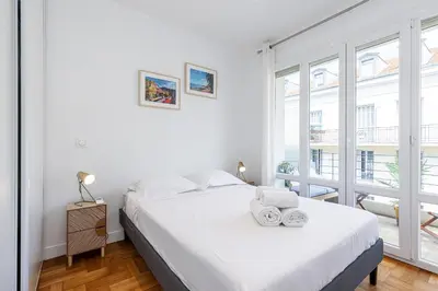 a white bedroom with a bed and a window at Quiet 1 Bdr Downtown Terrace AC & Parking in Nice