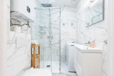 a white bathroom with a shower and a toilet at Quiet 1 Bdr Downtown Terrace AC & Parking in Nice