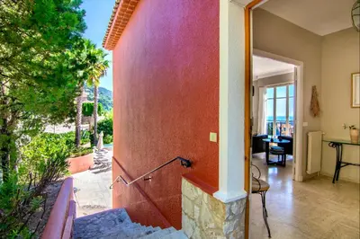a home with a red wall with a patio at Villa Soleil d'Or in Villefranche-sur-Mer