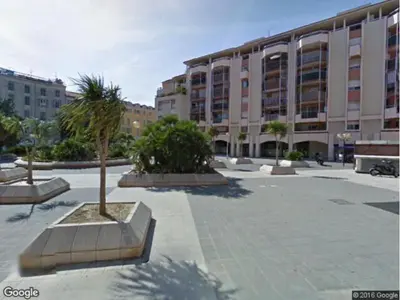 a large building with a palm tree in a courtyard at Appartement 6 pers Port de Nice, mer et Vieux-Nice à pied in Nice