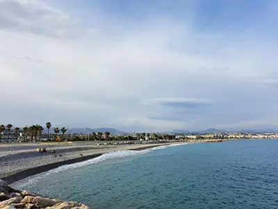 a beach with people on the sand and the water at La Villa Castel - Haut de villa - parkings- 3 chambres - 8 couchages - jardin - barbecue in Cagnes-sur-Mer