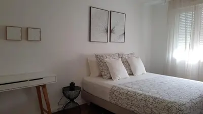 a white bedroom with a bed and a desk at Nice Bel Appartement Vue Mer climatisé avec Grande Terrasse in Nice