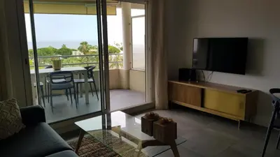 a living room with a couch and a tv and a balcony at Nice Bel Appartement Vue Mer climatisé avec Grande Terrasse in Nice