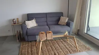 a living room with a blue couch and a glass table at Nice Bel Appartement Vue Mer climatisé avec Grande Terrasse in Nice