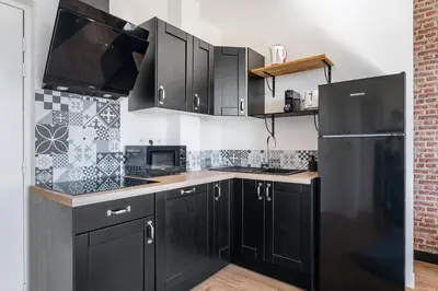 a kitchen with black cabinets and a black refrigerator at Nice Renting - CAMBRAI - Luxurious Sea View Terrasse - King Bed - Parking - AC - fully equipped in Nice