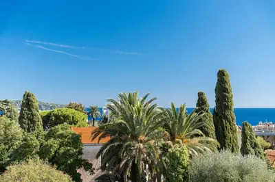a view of a garden with palm trees and the ocean at Nice Renting - CAMBRAI - Luxurious Sea View Terrasse - King Bed - Parking - AC - fully equipped in Nice