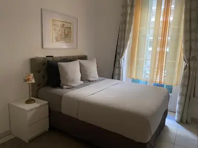 a bedroom with a bed with white sheets and a window at The Grand Riviera Apartments Nice - Top Choice in Nice in Nice