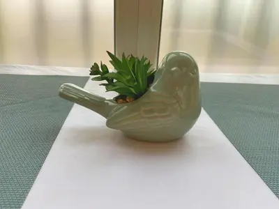 a green bird vase with a plant in it at Coquet logement front de mer in Cagnes-sur-Mer