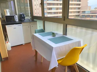 a kitchen with a white table and yellow chairs at Coquet logement front de mer in Cagnes-sur-Mer