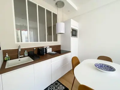 a white kitchen with a sink and a table at Mediterranee - un trois pièces à deux pas de la plage in Nice