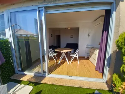 a sliding glass door leading to a patio with a table at L'Eau-Dyssée, clim, parking privé, jardin in Saint-Laurent-du-Var