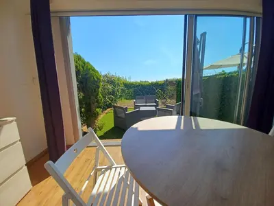 a wooden table and chairs in a room with a large window at L'Eau-Dyssée, clim, parking privé, jardin in Saint-Laurent-du-Var