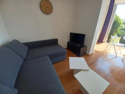 a living room with a couch and a clock on the wall at L'Eau-Dyssée, clim, parking privé, jardin in Saint-Laurent-du-Var