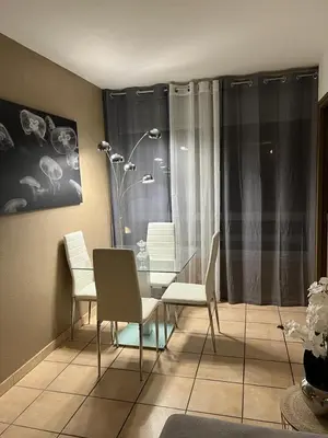 a dining room with white chairs and a table at Appartement 2 pièces Nice in Nice