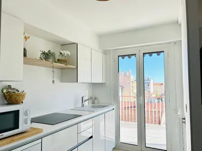 a kitchen with white cabinets and a balcony at PALAIS ROYAL - Appartement tout confort in Nice