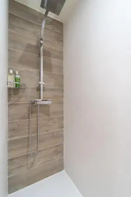 a shower in a bathroom with a wooden wall at Old Town Nice Renovated 2BR Near Beaches & Cours Saleya in Nice