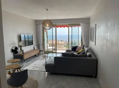 a living room with a black couch and a table at Exceptional sea view, tennis, parking, WiFi in Nice