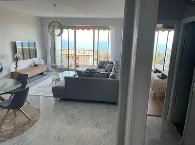 a living room with a couch and a table at Exceptional sea view, tennis, parking, WiFi in Nice