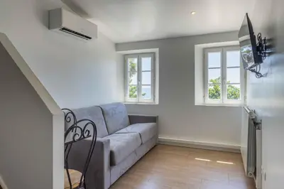 a living room with a couch and two windows at Appartements Vivo in Cagnes-sur-Mer