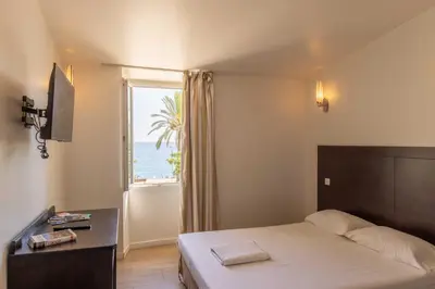 a bedroom with a bed and a window with the ocean at Appartements Vivo in Cagnes-sur-Mer