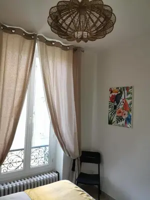 a bedroom with a bed and a window with a chandelier at Aston - Appartement Centre Ville Massena in Nice