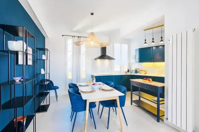 a kitchen with blue cabinets and a white table and chairs at COSY GARNIER AP4281 by Riviera Holiday Homes in Nice