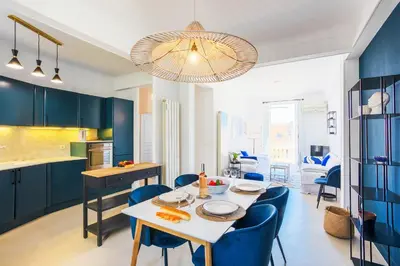 a kitchen and dining room with blue cabinets and a table and chairs at COSY GARNIER AP4281 by Riviera Holiday Homes in Nice