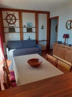 a living room with a table and a blue couch at Maeva in Saint-Laurent-du-Var