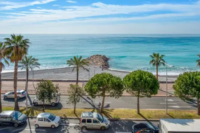 a view of a beach with palm trees and cars at Appartement Rivage - Welkeys in Cagnes-sur-Mer