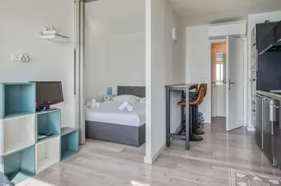 a bedroom with a bed and a desk with a television at Appartement Rivage - Welkeys in Cagnes-sur-Mer