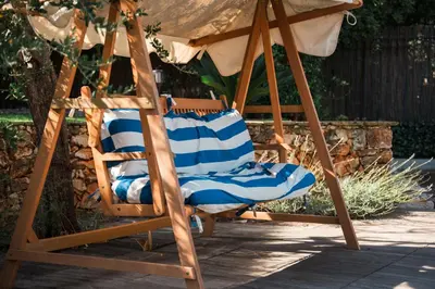 a wooden rocking chair with an umbrella and anolis at Charming Villa Saint-Jean-Cap-Ferrat in Saint-Jean-Cap-Ferrat
