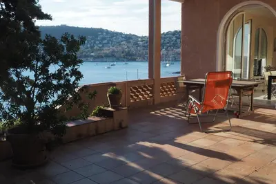 a table and chair on a balcony with a view of the water at Villa la Felicite in Saint-Jean-Cap-Ferrat